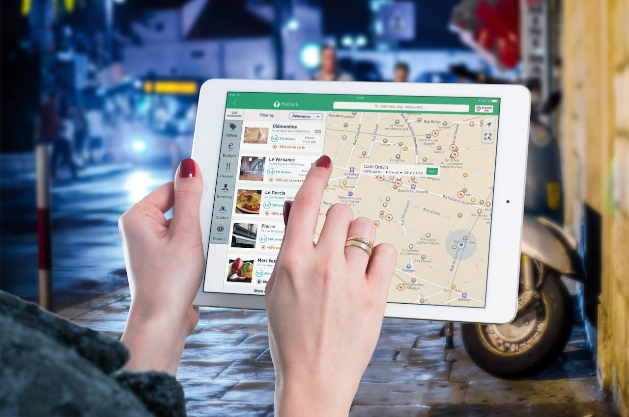 hero-img-01 Hands using a digital map on a tablet in an urban setting at night, illustrating navigation and technology.