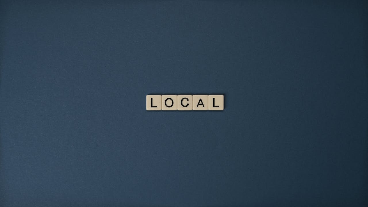 hero-img-02 Flat lay of Local in Scrabble tiles on a blue background, with ample copy space.